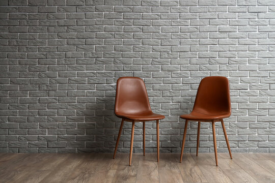 Stylish chairs near grey brick wall