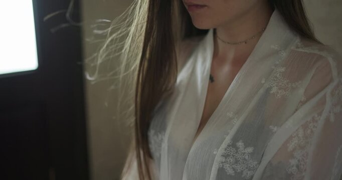 Close up of a young woman in white sheer robe with hair fluttering in slow motion
