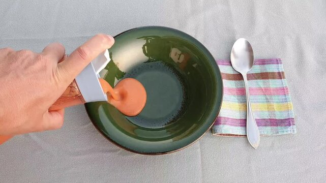 Man pouring Salmorejo, spanish cold tomato soup, into green bowl