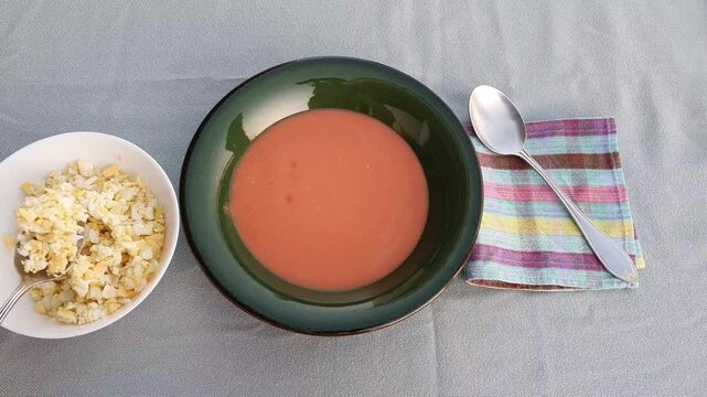 Adding diced boiled eggs to Spanish salmorejo, cold tomato soup.