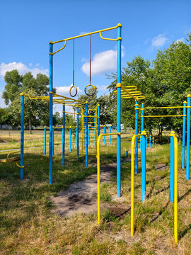 Yellow and blue outdoor sports complex with stationary training equipment gymnastic rings pull up bars and parallel bars in a residential neighborhood for exercise strength development and recreation