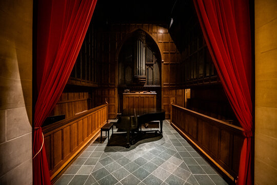 Washington, District of Columbia, United States - 06 May 2025: View of a grand piano and pipe organ inside the Washington National Cathedral, framed by red curtains.