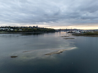 Obraz premium Cloudy Evening Over Burrard Inlet Riverfront With Bridge, Industrial Waterfront And Distant Vancouver Skyline