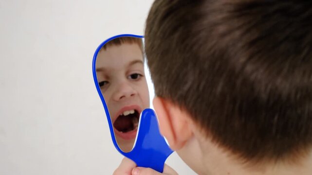 A child at the dentist's office examining his teeth in a mirror. Selective focus.