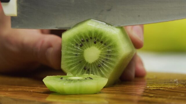 Large knife slicing up shaved kiwi on chopping board in slow motion
