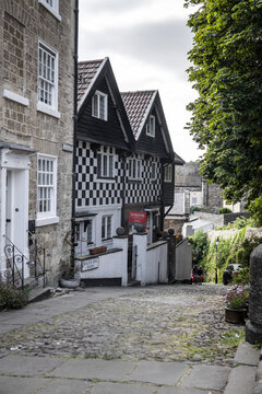 Knaresborough, England, United Kingdom - 14 July 2026: View of historic timber-framed houses with distinctive black and white checkered facades lining a steep cobblestone street.