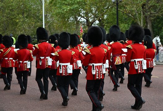London, United Kingdom - 10 October 2025: View of the Queen's Guard marching in their traditional red tunics and bearskin hats along the road near Buckingham Palace.