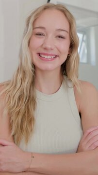 Vertical video: Smiling woman then laughing at offscreen cue in studio, wearing ribbed top, hoops