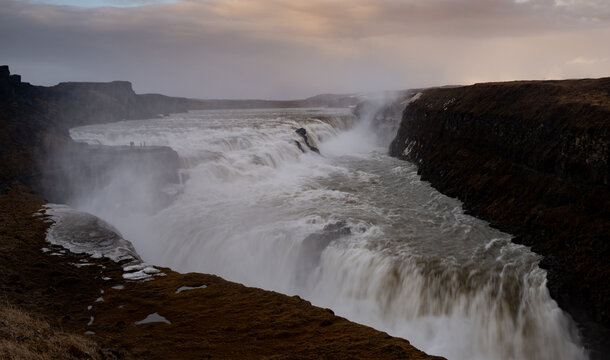 Powerful torrent of the hvita river cascading into a deep canyon, creating mist and spray under a cloudy sky at sunset. Gullfoss powerfull waterfall