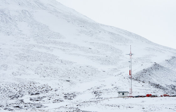 Mobile communications building and communication tower standing on an arctic snowy mountain slope Iceland blizzard weather