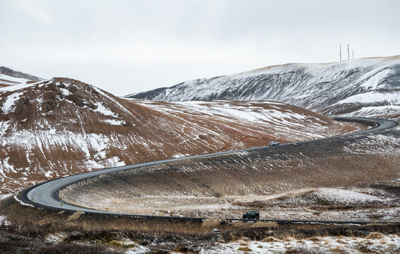 Cars traveling winding ring road through a vast, rugged winter landscape in iceland, namaskardh mountain pass . Iceland