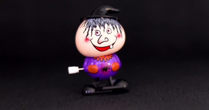 Playing with a cute mechanical wind-up Halloween character on a dark background. Halloween and preparations for it