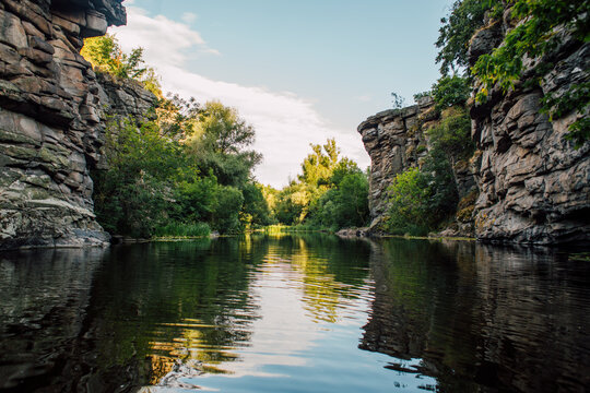 Steep Rocky Canyon Cliffs with Trees and Water Reflection