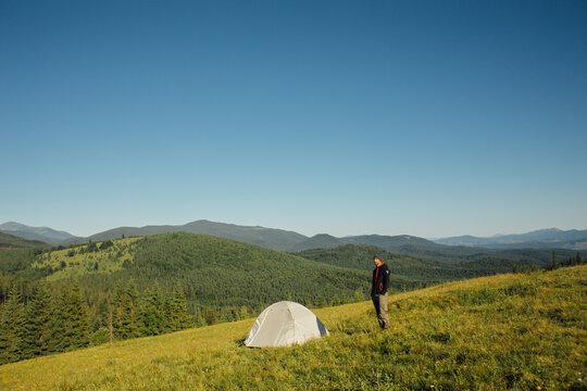 Tourist watching the mountain landscape near the tent