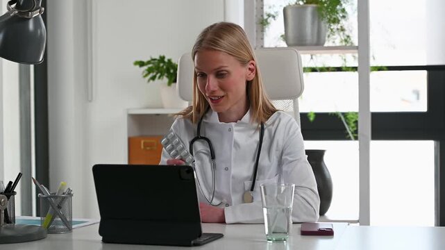 Female doctor conducting an online medical consultation from her office, showing medication and providing healthcare advice to a remote patient during a virtual appointment