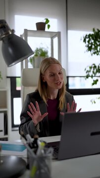 Professional businesswoman delivering an online presentation during a virtual meeting, explaining business results, strategy, and project updates in a contemporary office. Vertical video.