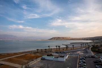 Fototapeta premium Peaceful Dead Sea Resort Beach with White Parasols and Scenic Waterfront in Israel, Scenic Dead Sea Beach with Resort Sun Umbrellas and Crystal Blue Water in Israel