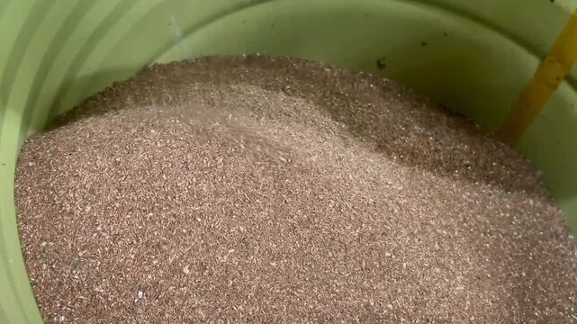 Close view of rounded mound composed of finely shredded copper granules inside ribbed green plastic container