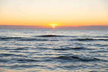 Fototapeta premium Minimalist seascape with a golden sunset over the calm sea and a clear sky.