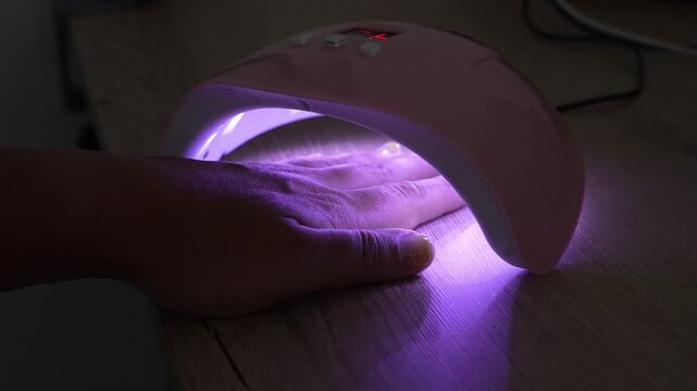 Woman Curing Gel Nail Polish Under UV LED Lamp at Home