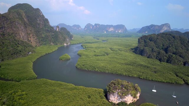 Aerial drone view of limestone islands surrounded by mangrove forest and winding waterways in Phang Nga Bay, Thailand. Tropical coastal landscape with lush greenery.