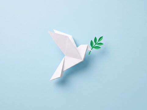 A white paper origami dove holding a green olive branch on a light blue background