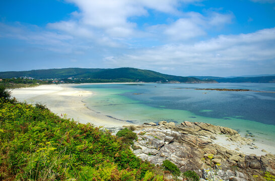 Idyllic summer landscape a sandy beach in sea cove, on the background of green mountains and blue sky, Fisterra, northern Spain