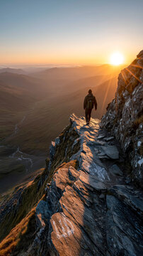 Lone hiker walks a precarious mountain edge at sunset