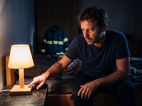 Feuerwehrmann schaltet nachts Lampe an im Schlafzimmer
