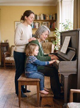 Gro&szlig;mutter spielt Klavier mit Enkelin und Tochter im Wohnzimmer