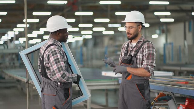 Two diverse factory workers discussing production process