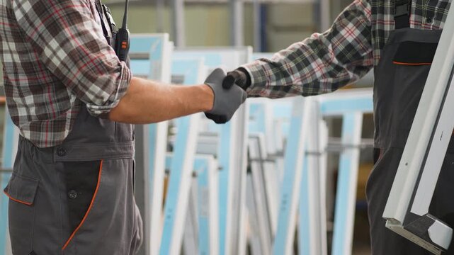 Two factory workers shaking hands agreement