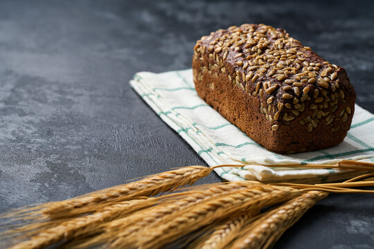 loaf Danish rye bread made from sourdough with whole grain flour and seeds on dark kitchen table.