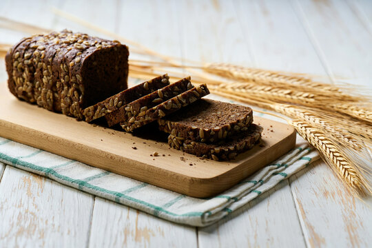 wholemeal rye bread with sunflower seeds on white kitchen table, selective focus.