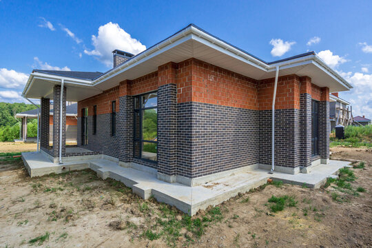 A newly built house features a modern design with a mix of brick and siding. The structure is located in a serene area surrounded by greenery and offers a spacious layout.
