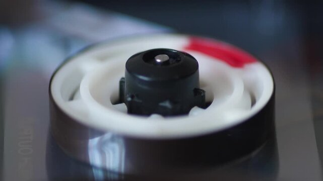 Close-up of a rotating reel spindle with magnetic tape on a vintage recorder deck. High-detail analog audio equipment playing sound in macro view.