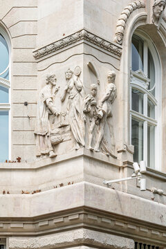 Close view of allegorical stone figures carved into the corner pilaster of the Hungarian National Bank facade in Budapest, Hungary