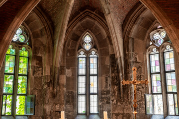 Obraz premium Gothic chapel interior with tall stained glass windows and a gilded cross at Buda Castle in Budapest, Hungary