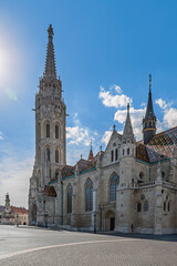 Obraz premium Full view of Matthias Church with its Gothic tower and colorful roof overlooking an empty square in Budapest, Hungary