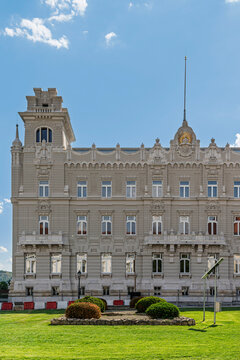 Gothic Revival stone facade of Archduke Joseph's Palace overlooking a manicured lawn with flowerbeds in Budapest, Hungary