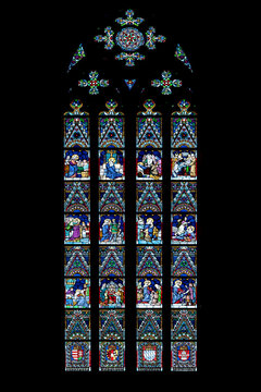 Gothic stained glass window with rose tracery and biblical figures against a dark background, Matthias Church, Budapest