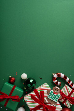 Christmas present with gingerbread cookie, candy cane and ornament on vertical green background for holiday