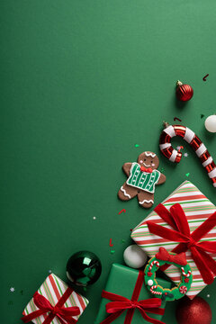 Christmas gifts and decorations with gingerbread cookie candy cane and ornaments for holiday celebration on green vertical backdrop