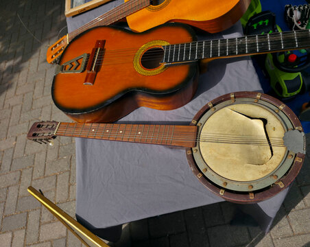 Vintage acoustic guitars and a rustic banjo on display at a market table in sunlight