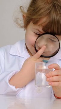Laboratory examination of a child with test tubes, reagents and a microscope. Selective focus.