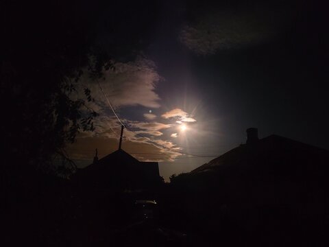 Glowing Moon in Cloudy Night Sky Over Village