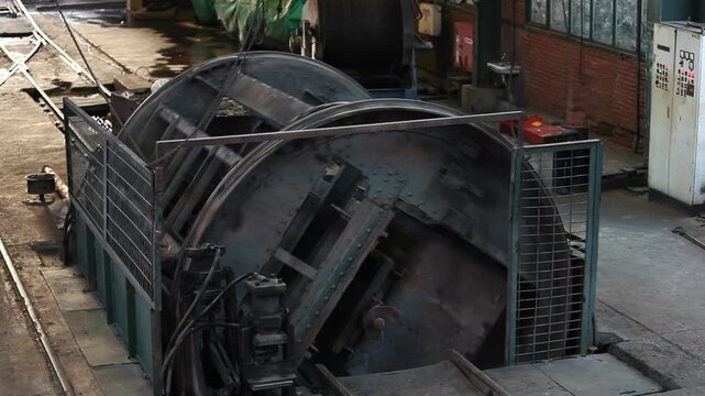 Heavy coal mine cart being emptied by a large rotary dumper mechanism in an industrial mining facility. Mining industry, coal processing, and heavy machinery concept.