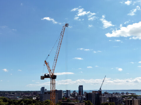 Tall construction crane against a blue sky with clouds in an urban development zone