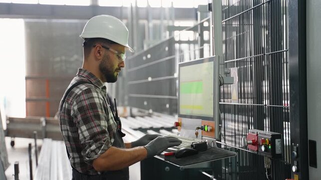 Factory engineer operating automated industrial machinery computer