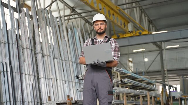 Industrial engineer using laptop in a metal profile warehouse